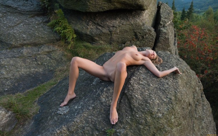 Naked woman lies on stones