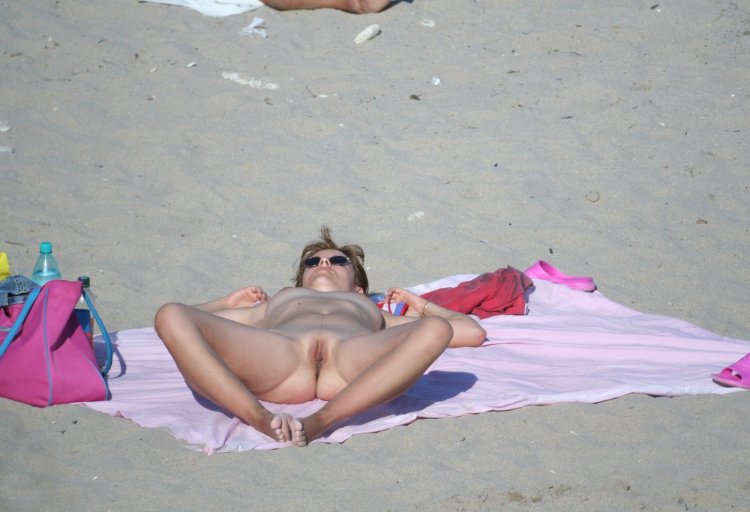 Sunbathing on the beach spreading his legs